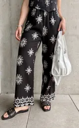Pantalón negro con estampado de rombos blancos, de corte recto y tiro alto.