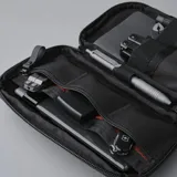 Riñonera negra con correa ajustable, confeccionada en material impermeable xPac X21. Cuenta con 7 bolsillos internos y 2 externos, organizador con apertura de 180°, espacio para cables y cargadores, detalles en color ladrillo y cierres impermeables.