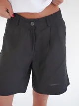 Bermuda negra de tiro medio, corte ancho, con bolsillos laterales y un ojal en la parte trasera.