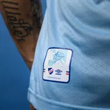 Camiseta de fútbol Umbro del Club Nacional de Football, modelo Away 3. Diseño celeste con detalles en azul y rojo en cuello y mangas. Incluye logo de Umbro, escudo del club y sponsors.