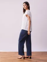 Blusa blanca labrada con cuello a la base, escote en V y aplique metálico. Tiene mangas cortas superpuestas.