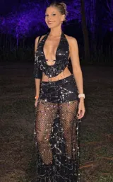 Conjunto de dos piezas negro, compuesto por un top halter con abertura frontal y detalle de hebilla dorada, y una falda larga transparente con lentejuelas plateadas dispuestas en líneas diagonales y flecos colgantes.