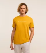 Remera de hombre color mostaza, de corte comfort, con cuello redondo y manga corta. Estampa frontal con la frase "La confiance est le secret du succès" en color blanco.