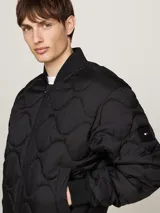 Campera bomber negra acolchada, con cuello estilo béisbol, cierre de cremallera, dos bolsillos delanteros ribeteados, cuello, puños y bajo de punto canalé.
