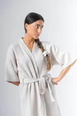 Bata kimono corta color beige, confeccionada en tela waffle de algodón. Tiene mangas al codo, lazo de ajuste en la cintura y detalle de vivo en la solapa.