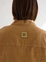 Chaqueta color marrón claro de lino y algodón, con cuello mao, cierre frontal con botones de madera y bolsillos laterales.