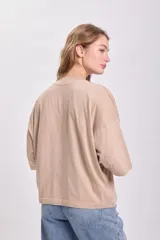 Remera color beige de corte holgado, con cuello alto y mangas 3/4.