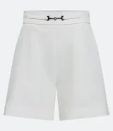 Short de vestir blanco de corte sastrero, con cintura alta, bolsillos laterales y detalle de hebilla metálica plateada en la cintura.