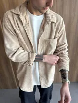Sobrecamisa color beige de pana con cuello clásico, cierre frontal con botones, manga larga con puños abotonados y bolsillo de parche en el pecho.