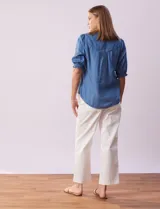 Blusa de lyocell color celeste, con cuello a la base, escote en V y botones. Delantera con bolsillo. Manga corta con terminación en punto smock.