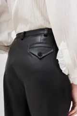 Pantalón negro de poliéster recubierto con poliuretano, corte cropped y tiro alto.