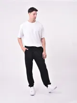 Pantalón de jogging negro con cintura elástica y cordón ajustable. Corte holgado con puños elásticos en los tobillos.