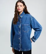 Camisa oversized de jean azul, con cuello padre, mangas largas con puños abotonados y cierre frontal con botones. Incluye un bolsillo aplicado en el pecho y bajo redondeado.
