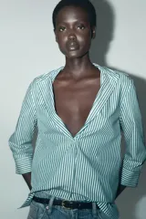 Camisa de mujer con cuello solapa y manga tres cuartos con estampado a rayas verticales verdes y blancas. Cierre frontal con botones ocultos.