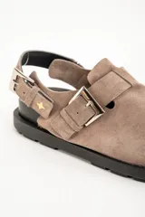 Zueco color visón de cuero con hebillas plateadas y suela negra.