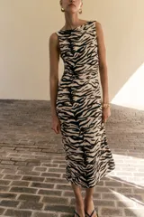 Vestido tobillero sin mangas en punto de crepé con estampado de cebra. Modelo de corte ajustado con escote bote drapeado y espalda abierta con sección girada en la cintura.