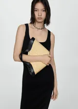Bolso de mano tipo clutch, confeccionado en paja color beige con detalles y asas de cuero sintético negro.