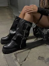 Bota de caña media de ecocuero color negro, con suela track, cierre lateral y tres hebillas decorativas con cierre de cremallera frontal.