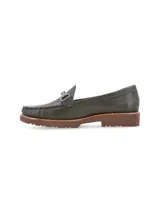 Mocasín de cuero negro con detalle de hebilla metálica plateada.