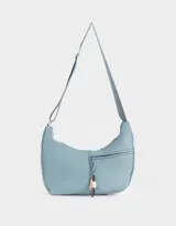 Cartera tipo saca de tela deportiva color celeste, con correa regulable, cierre superior y bolsillo frontal con cierre. Incluye charm lateral.