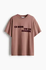 Remera oversized color marrón claro con estampado con la frase "Ce Soir On Va Danser" en color borgoña.