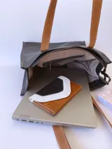 Bolso tipo tote bag de cuero negro con forro de tela, doble asa de cuero color suela, bolsillo frontal y bolsillo interno.