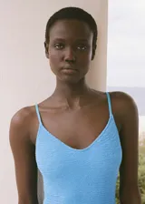 Traje de baño entero celeste con textura y tirantes finos.