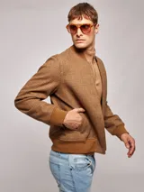 Campera bomber marrón con estampado a cuadros, cuello, puños y ruedo acanalados. Cierre frontal con cremallera.