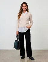 Buzo de hilado fino color beige con cuello y ruedo de gasa blanca que simula una camisa debajo. Presenta escote en V y mangas largas.