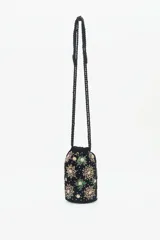 Cartera tipo tote bag de terciopelo negro con bordados de flores y estrellas de lentejuelas y mostacillas de colores. Tiene doble asa de cordón trenzado negro con cuentas en los extremos.