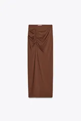Falda midi color marrón chocolate, de tiro alto con cintura elástica, detalle de frunces en un lateral y abertura frontal.