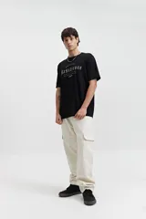 Remera color crema de manga corta con cuello redondo y estampado frontal con la palabra 'Resilience' en tipografía gótica.