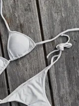 Conjunto de bikini azul con corpiño de triángulos movibles con almohadillas desmontables, que se ata al cuello y a la espalda. La bombacha es vedetina con tiritas a los costados para atar a medida de la cadera.