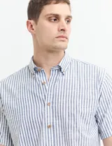 Camisa de manga corta a rayas verticales celestes y blancas, con cuello abotonado y corte clásico.