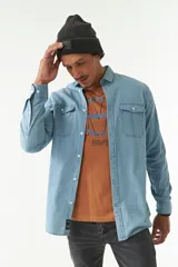 Camisa de jean azul de manga larga con dos bolsillos frontales con solapa abotonada.