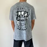 Remera gris con efecto acid wash y estampado en el pecho de una pelota de baloncesto con llamas y texto.