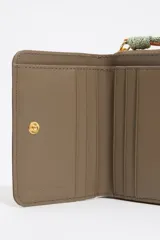 Billetera pequeña color marrón con cierre de cremallera y correa de mano con el logo de la marca.