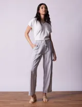 Pantalón largo de lino estampado a rayas verticales en tonos celeste, gris y blanco. Tiene pretina ancha elastizada con lazo ajustable.
