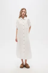 Vestido camisero midi negro de corte holgado, con cuello camisero, mangas cortas con trabillas, cierre frontal con botones, bolsillo en el pecho y bolsillos laterales.