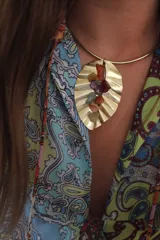 Collar rígido dorado con dije en forma de hoja con piedras de colores.