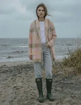 Cárdigan largo de tejido de punto con diseño a cuadros en tonos rosados y beige/gris. Presenta cuello chal y terminaciones con flecos largos en el borde frontal.