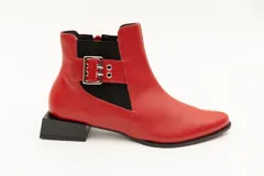 Botín de cuero rojo con elásticos laterales negros, aplique de hebilla metálica y taco cuadrado bajo. Cierre con cremallera lateral.