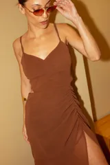 Vestido marrón con escote corazón, breteles finos y falda midi con frunces y abertura lateral.