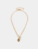 Collar corto dorado multicadena con eslabones de distintos grosores y dijes místicos con piedra ojo de tigre, corazón y letra C con strass.