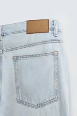 Pantalón de jean azul de corte recto, con cinco bolsillos, efecto lavado y cierre frontal con botonadura.
