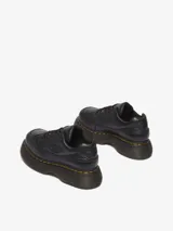 Zapatos Dr. Martens Buzz 5i de cuero negro con textura granulada, suela de plataforma gruesa con pespuntes amarillos, cierre de cordones y logo de la marca en relieve en el lateral.