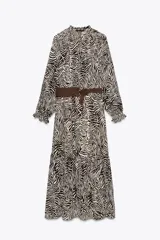 Vestido midi con estampado animal cebra en tonos blanco y negro, cuello redondo con lazada ajustable, manga larga con puños elásticos, forro interior y cinturón marrón con hebilla metálica.