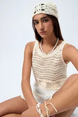 Top tejido al crochet color crudo, sin mangas y con cuello redondo.