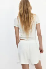 Short blanco con textura arrugada, cintura elástica y cordón ajustable.