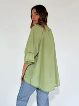 Blusa blanca de mangas 3/4 con volados y escote en V con cordones.